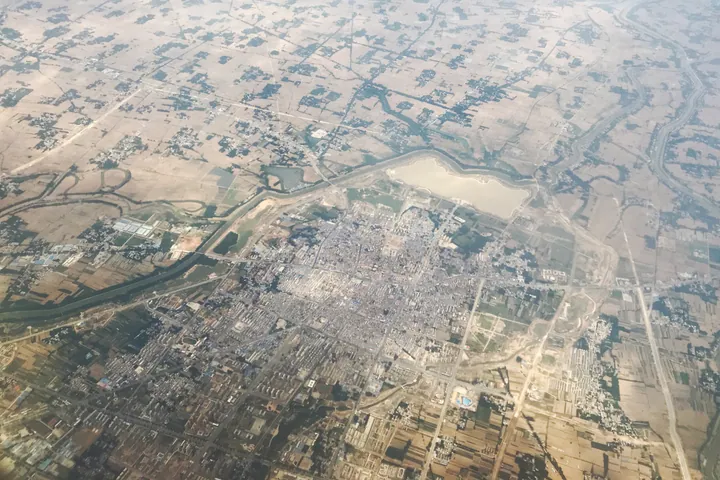 An aerial photograph showing Xincai County town beside a lake, surrounded by farmland