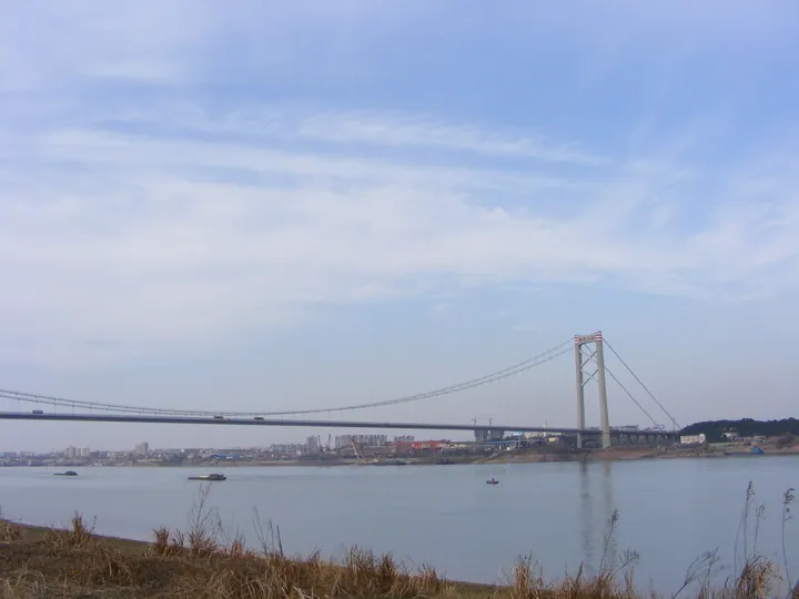 Long suspension bridge crossing the Yangtze River with boats below