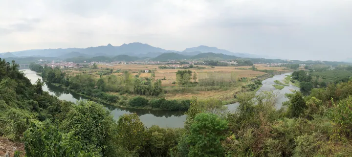 A winding river through farmland and forested hills near Anlu Village in Yuan'an County