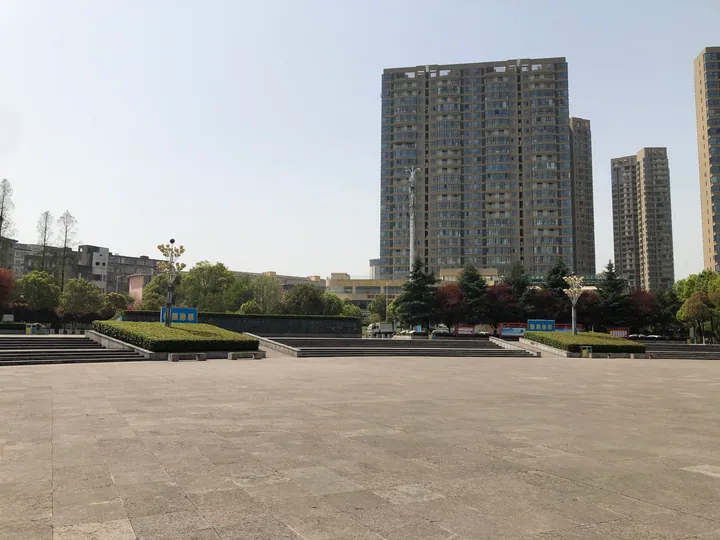 A paved plaza in Qing River Park, Yidu, with apartment towers in the background