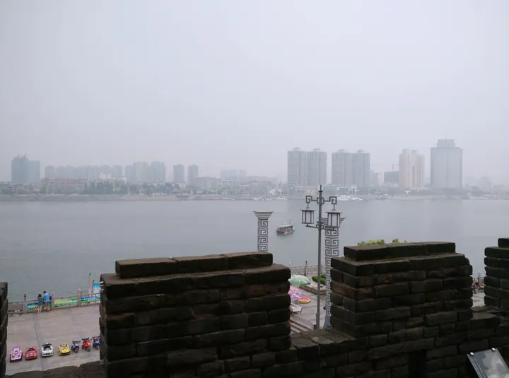 Historic city wall in the foreground with the Fancheng skyline across the river