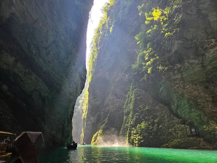 Boats on turquoise water in a dramatic narrow limestone gorge in Hefeng County