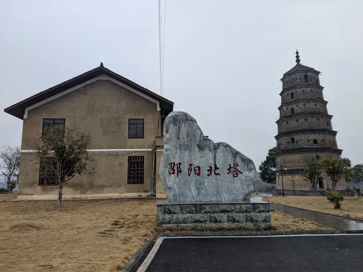 A tall brick pagoda beside a stone marker reading Shaoyang North Pagoda