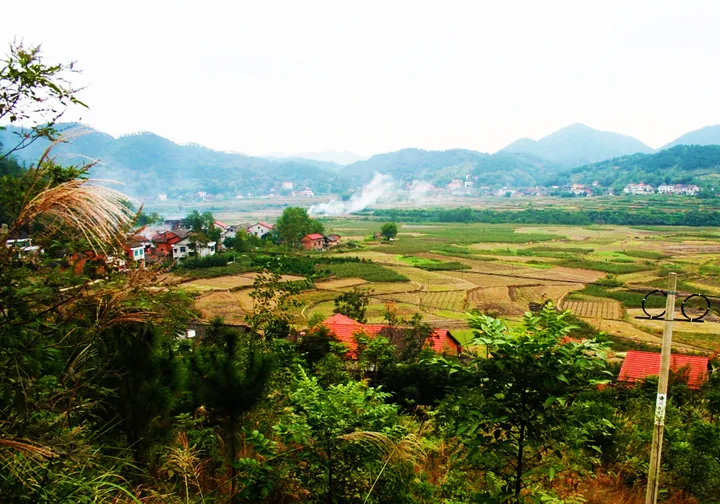 A rural village with red-roofed houses amid rice fields and hills in Li County