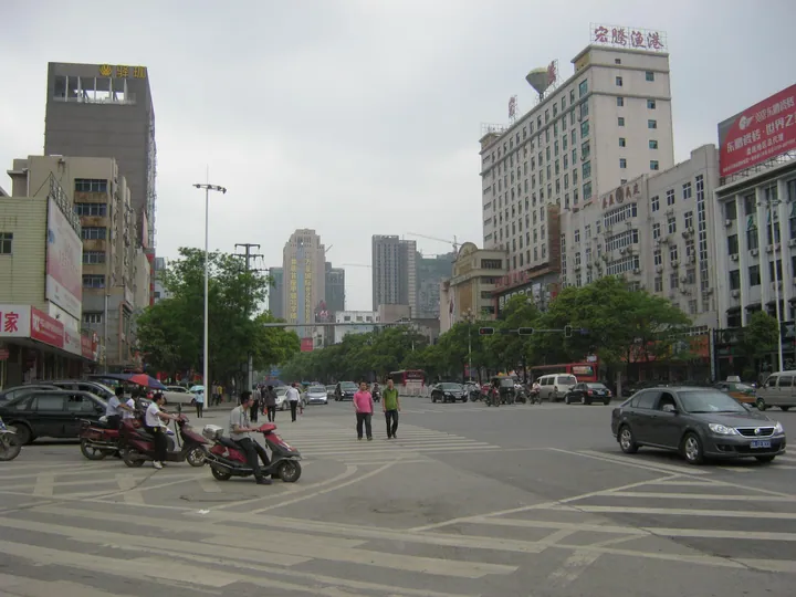 Urban street intersection with buildings, traffic and pedestrians in Loudi