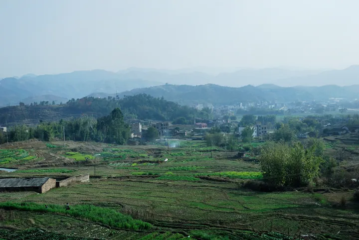 Rice paddies, hills and a small village along a road in Xinfeng County