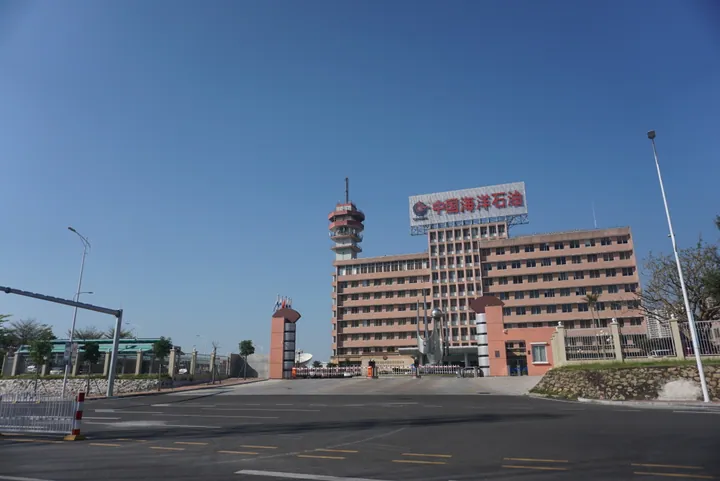 A pink office tower with a China National Offshore Oil Corporation sign and entrance gate in Potou District