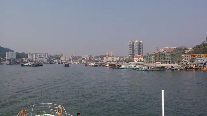 Fishing boats moored along a harbour waterfront with a town skyline behind