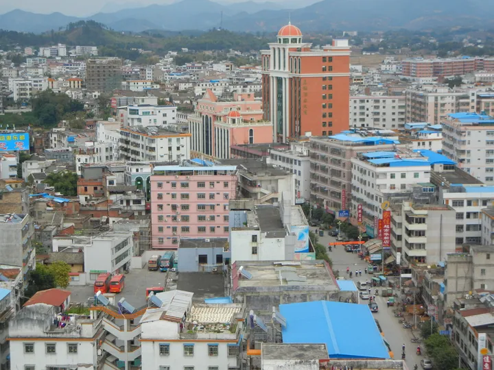A dense townscape of multi-storey buildings with hills in the background