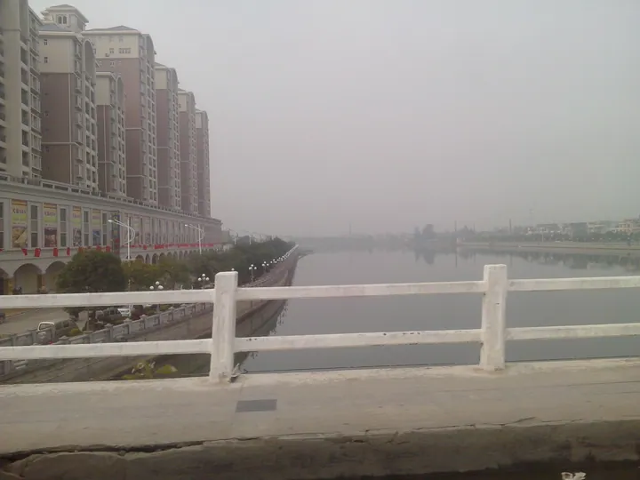 Riverside avenue with apartment buildings under a hazy sky in Yangchun