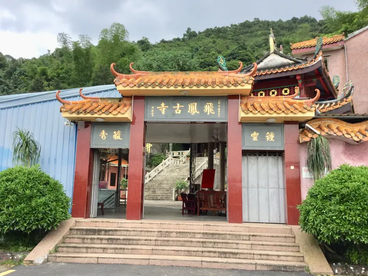 The ornate red and gold entrance gate of a Chinese temple with a staircase behind