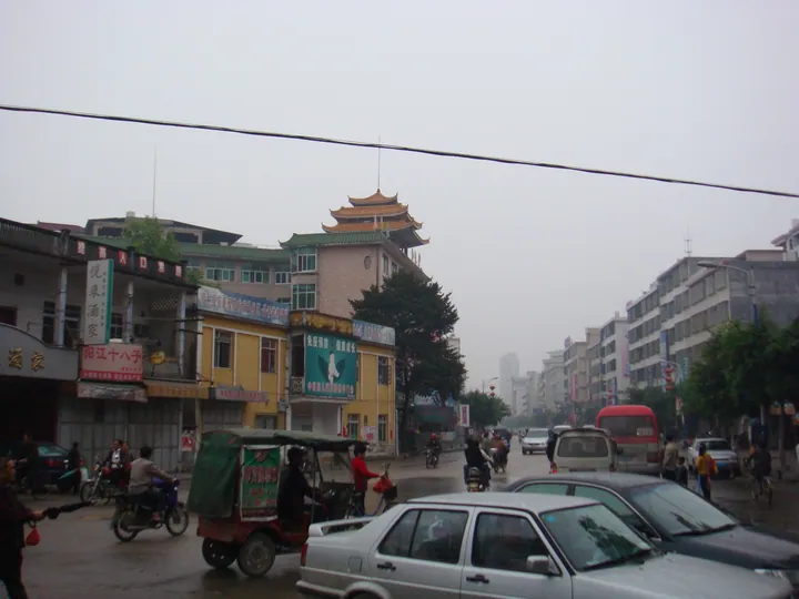 Street with traffic, shops and a traditional pagoda-style tower in Hepo, Jiexi County