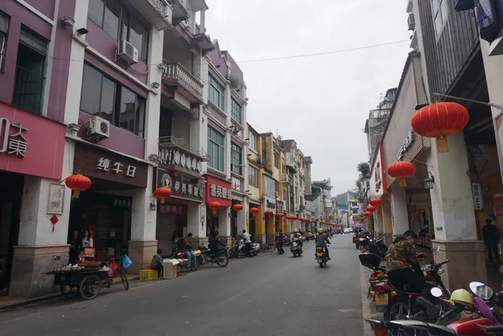 A street lined with veranda-style shopfronts and red lanterns in Ducheng Town, Yunan County