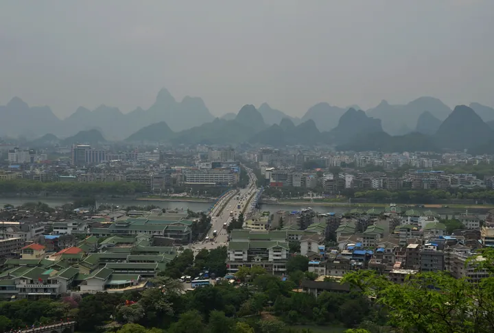 A river and city skyline in front of a row of karst mountain peaks