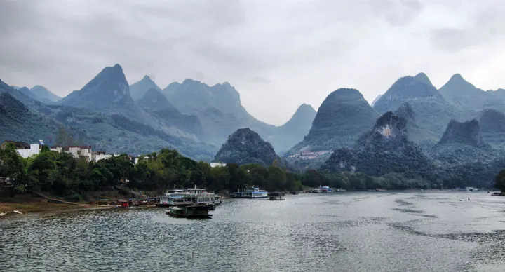 Bamboo rafts carrying tourists on a river surrounded by dramatic karst peaks