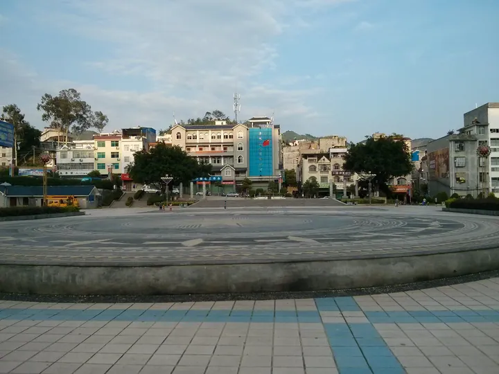 Open plaza with buildings and mountains in Xilin County