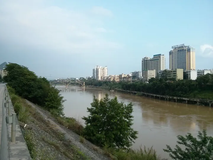 A riverside view of a city with an arched bridge and high-rise buildings