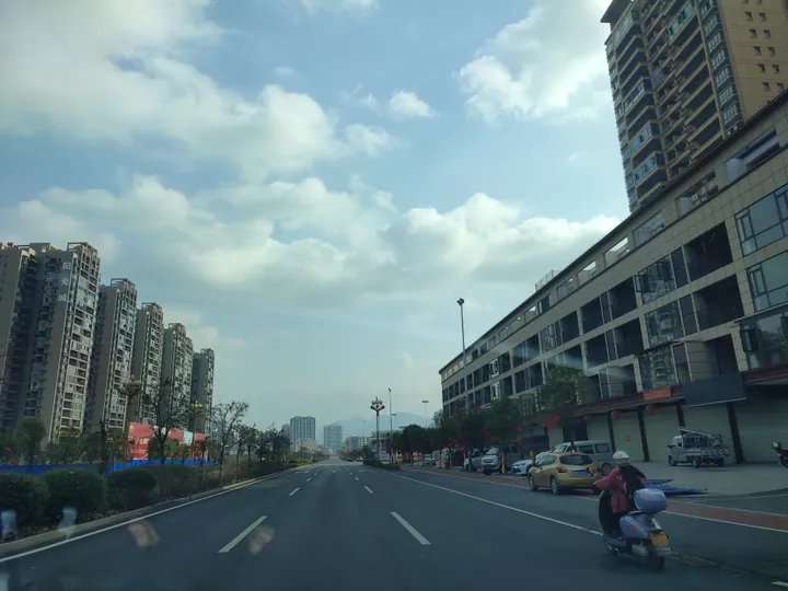 A city street lined with high-rise apartment buildings under a blue sky