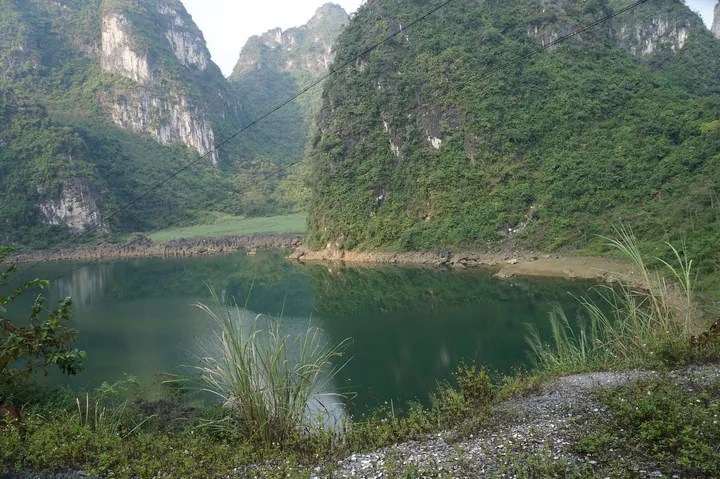 Still green water reflecting dramatic karst limestone peaks in a narrow gorge