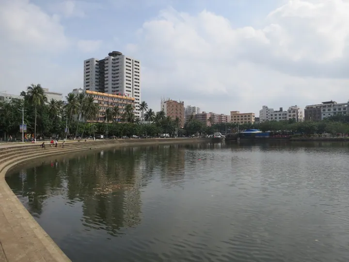 Lake waterfront with palm trees and high-rise buildings in Qiongshan District