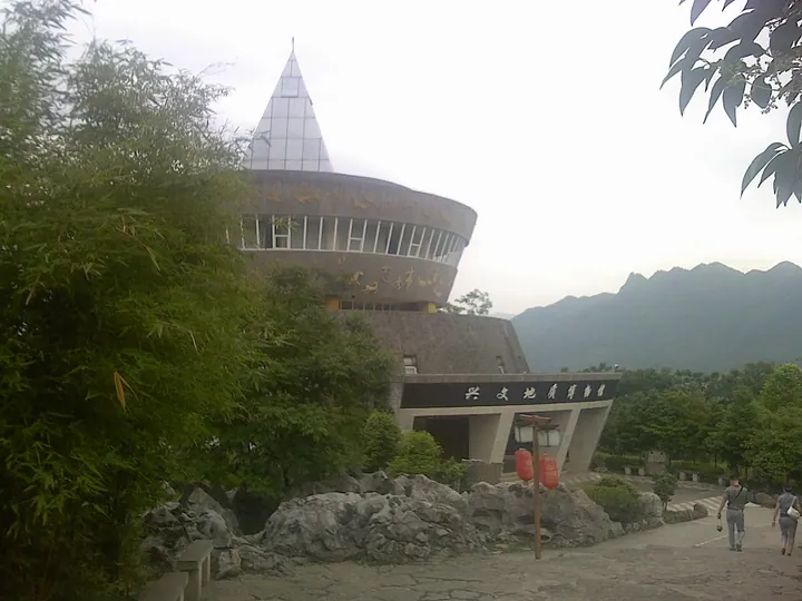 The circular Xingwen Geological Museum building with mountains behind, in Xingwen County