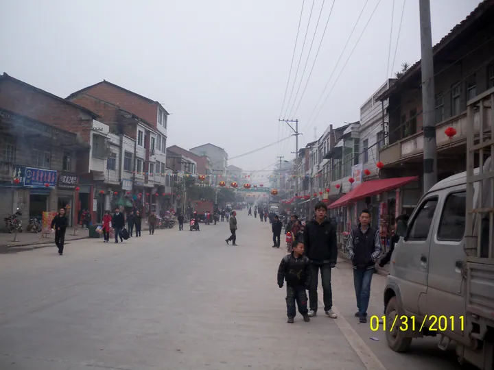 Overcast street scene with pedestrians and red lanterns in Oujia Town, Linshui County