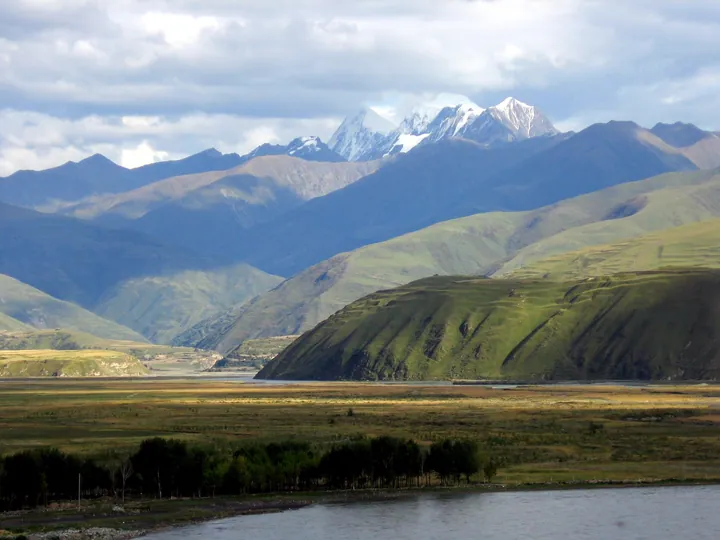 A wide grassland valley below snow-capped peaks near Ganzi