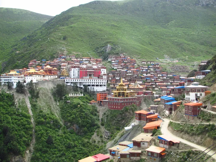 Katok Monastery, a large Tibetan Buddhist monastery complex on a green hillside in Baiyu County