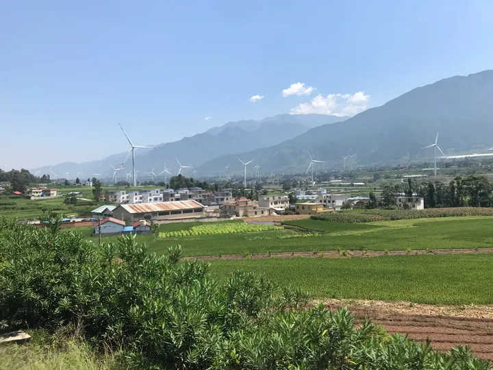 Village and wind turbines on a hillside in Dechang County