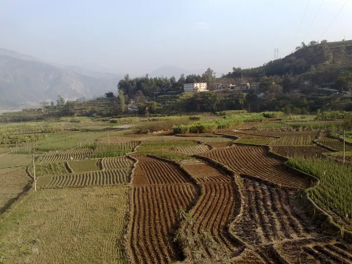 Terraced fields leading to a small village on a hillside in Qiaojia County
