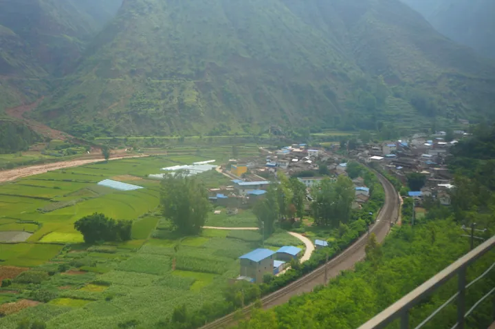 A farming village and railway line in a green valley in Mouding County