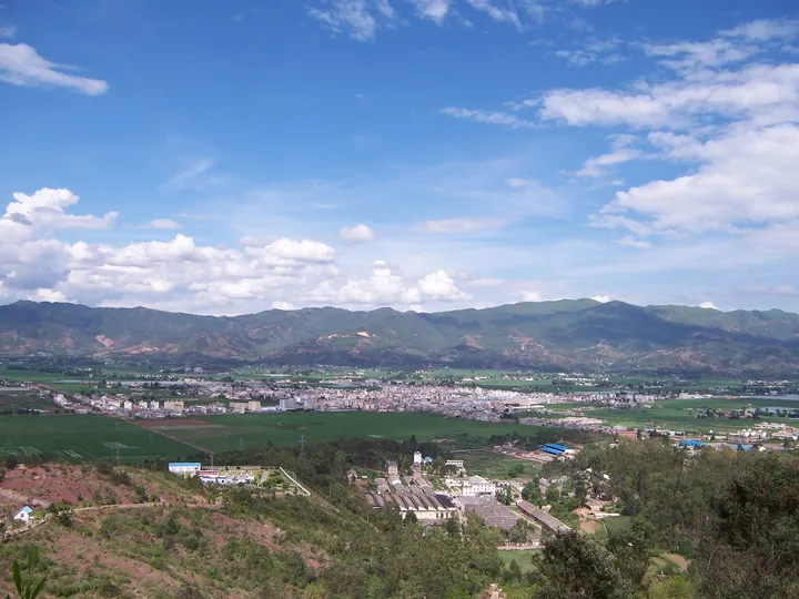 A wide valley town surrounded by green mountains under a blue sky
