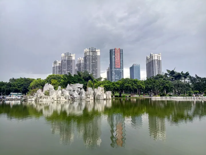 City park lake with a rockery island and high-rise skyline behind