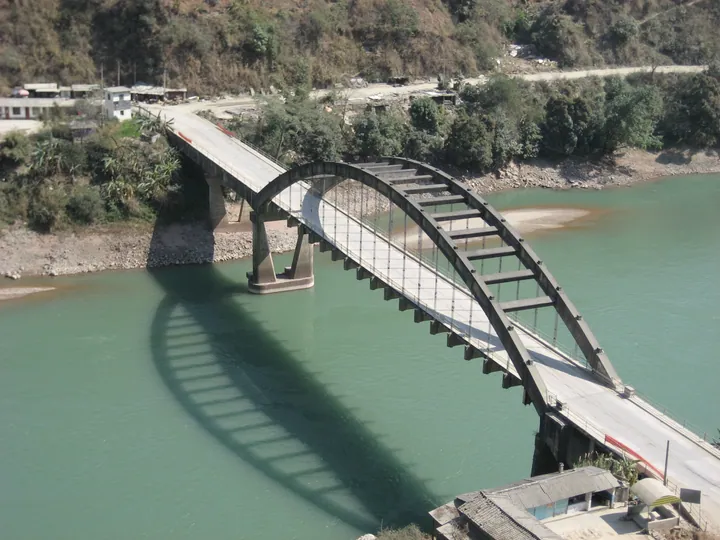 A steel arch bridge crossing a green river in Yongping County