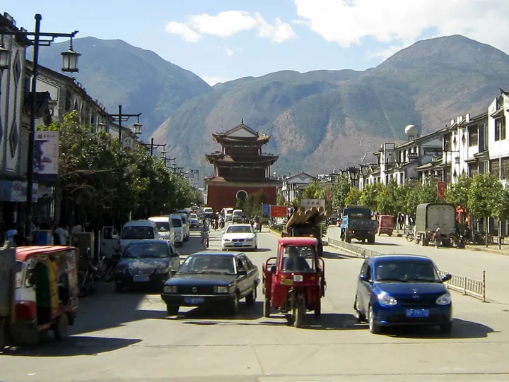 A street lined with shops leading to the Yunhe Pagoda, with mountains behind, Heqing County