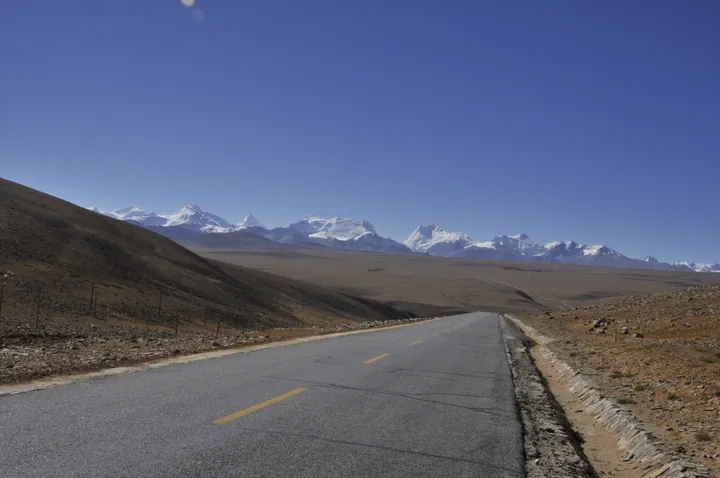 Empty highway leading toward snow-capped Himalaya peaks, Nyalam County