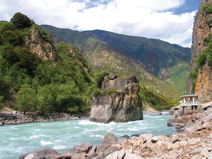 A rock pillar and riverside pavilion in the turquoise Nyang River, Gongbo'gyamda County