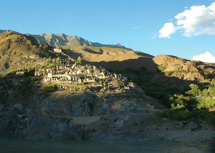 Terraced river valley with a small reservoir and distant village
