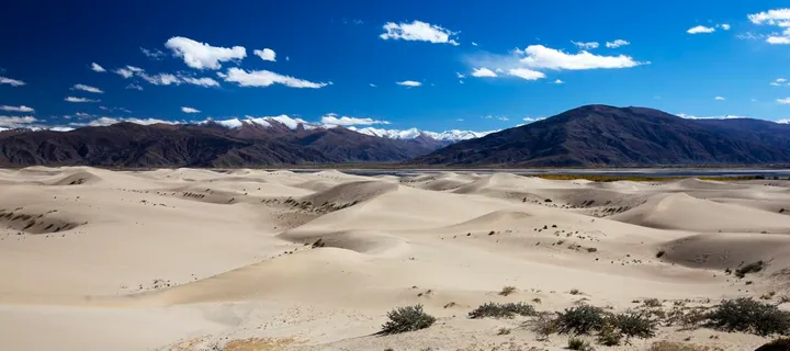 Pale sand dunes with mountains behind, Zhanang County