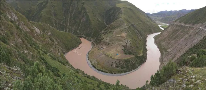 A muddy river winding through green hills at Dula Chok in Biru County