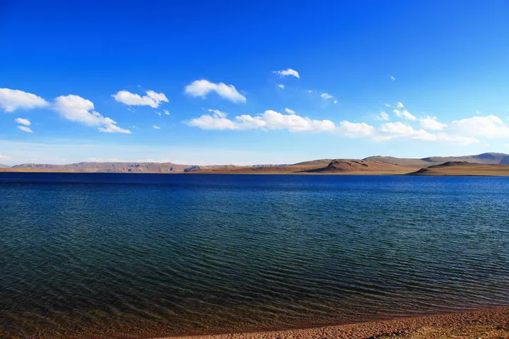 Blue lake bordered by grassy hills in Xainza County