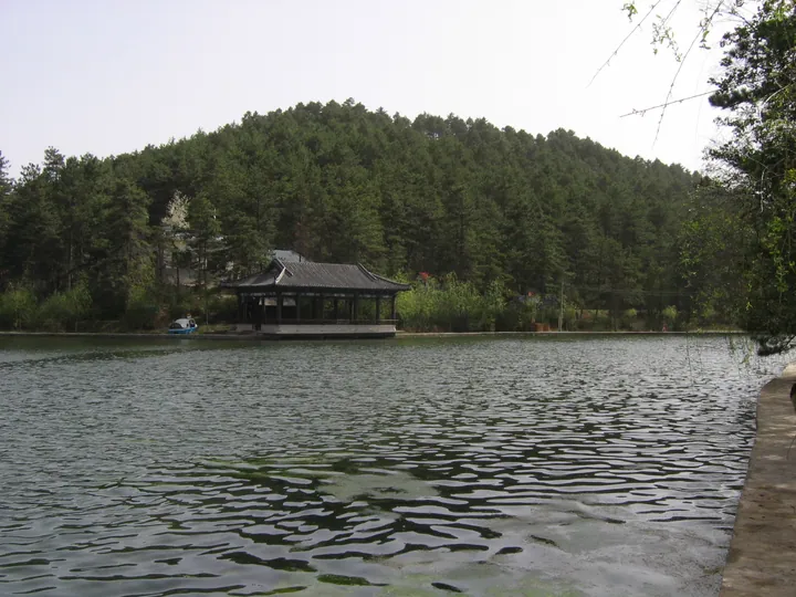 Lakeside pavilion surrounded by pine forest at Yuhua Palace
