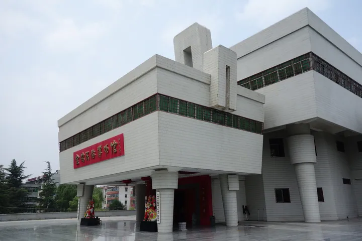 The white modern exterior of the Baoji Folk Custom Museum with statues at its entrance