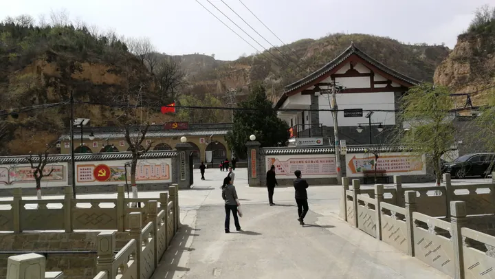 Visitors in a courtyard in front of a traditional-style building at the Liangjiahe site in Yanchuan County