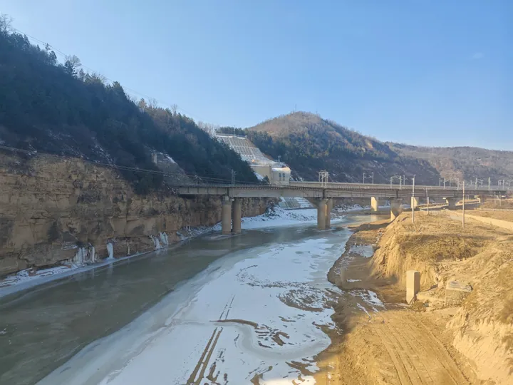 A frozen river winding through a rocky canyon beneath a railway bridge near Ganquan, Yan'an