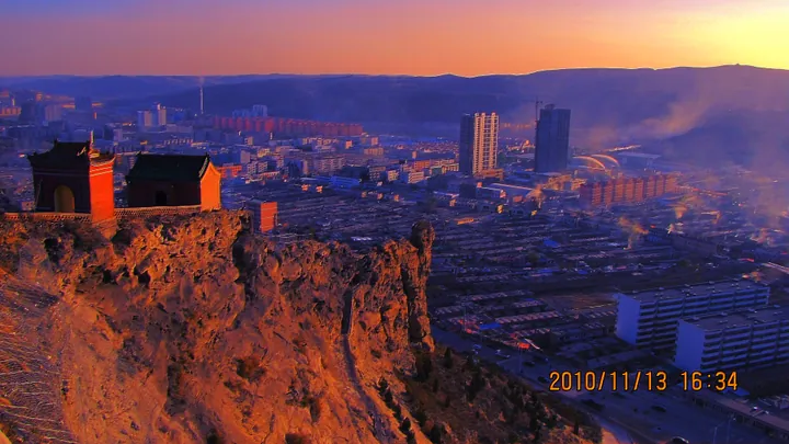 Temple pavilion on a cliff with Shenmu City below at dusk