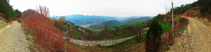 A winding mountain road through a hazy valley in Shangzhou District