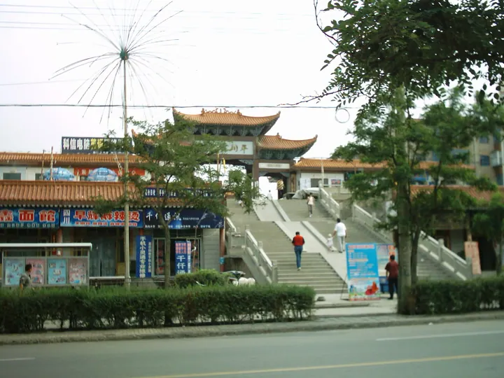 A Chinese-style gate archway at the top of steps above a shopping street in Pingchuan District
