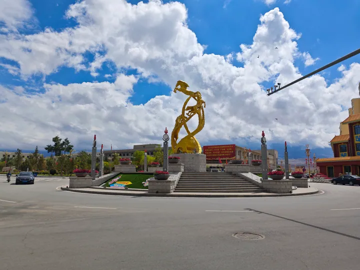 Golden statue on a landscaped roundabout in Subei county town under a blue sky
