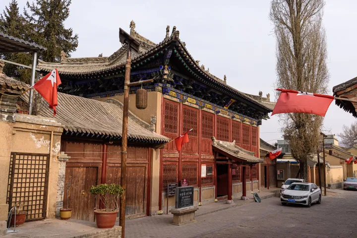 Traditional red-and-gold building with flags at the Hadapu Conference site, Tanchang County